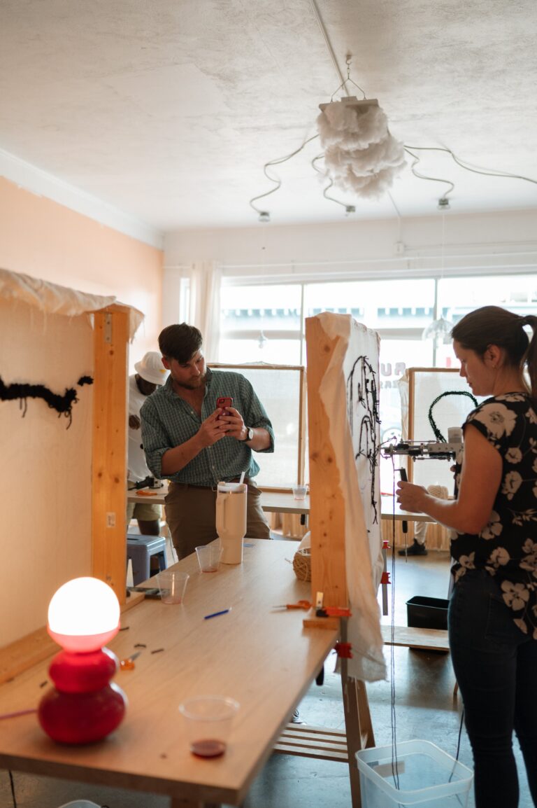 People working at tufting frames and a long table