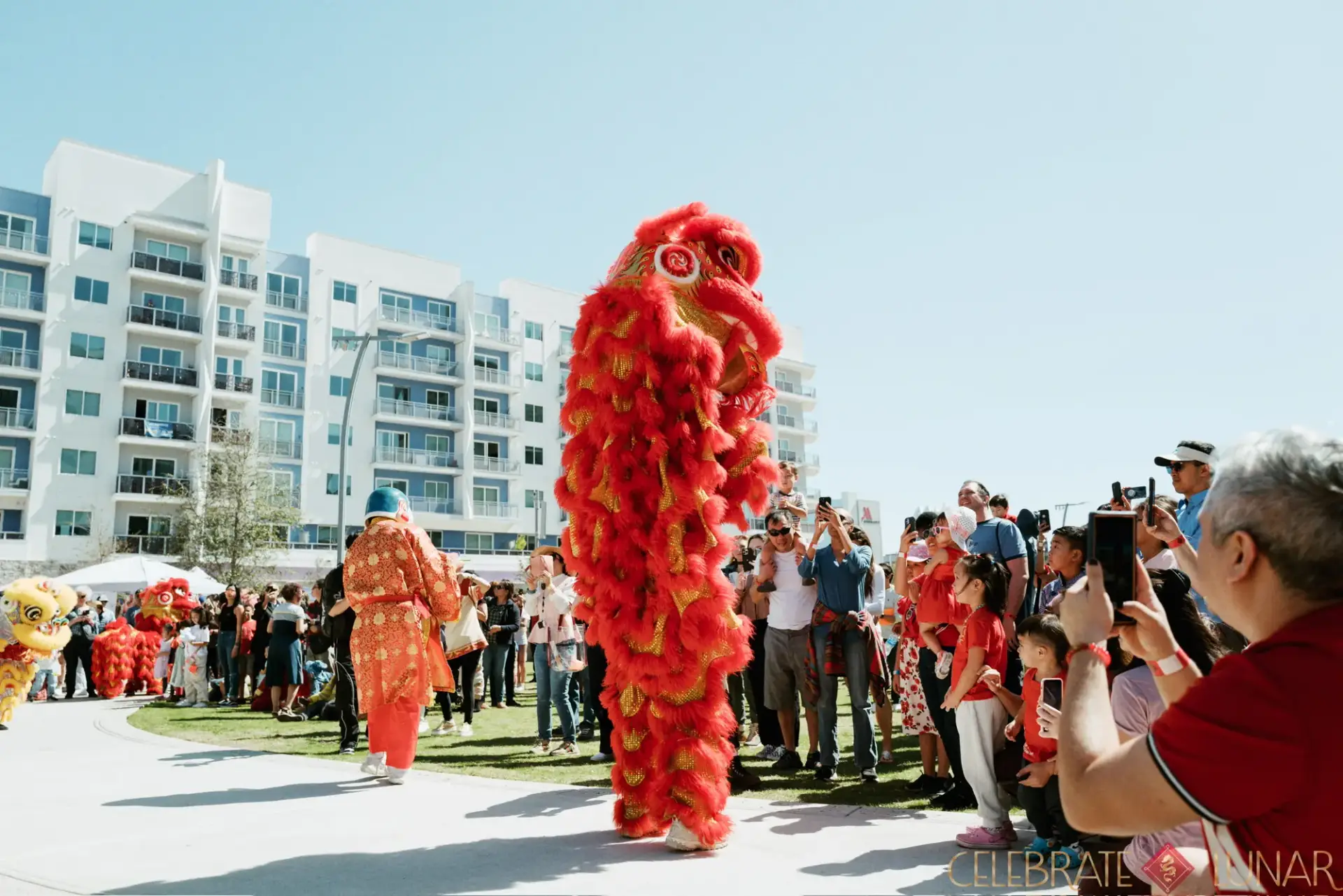 Red lion dancer surrounded by a cheering crowd at Celebrate Lunar