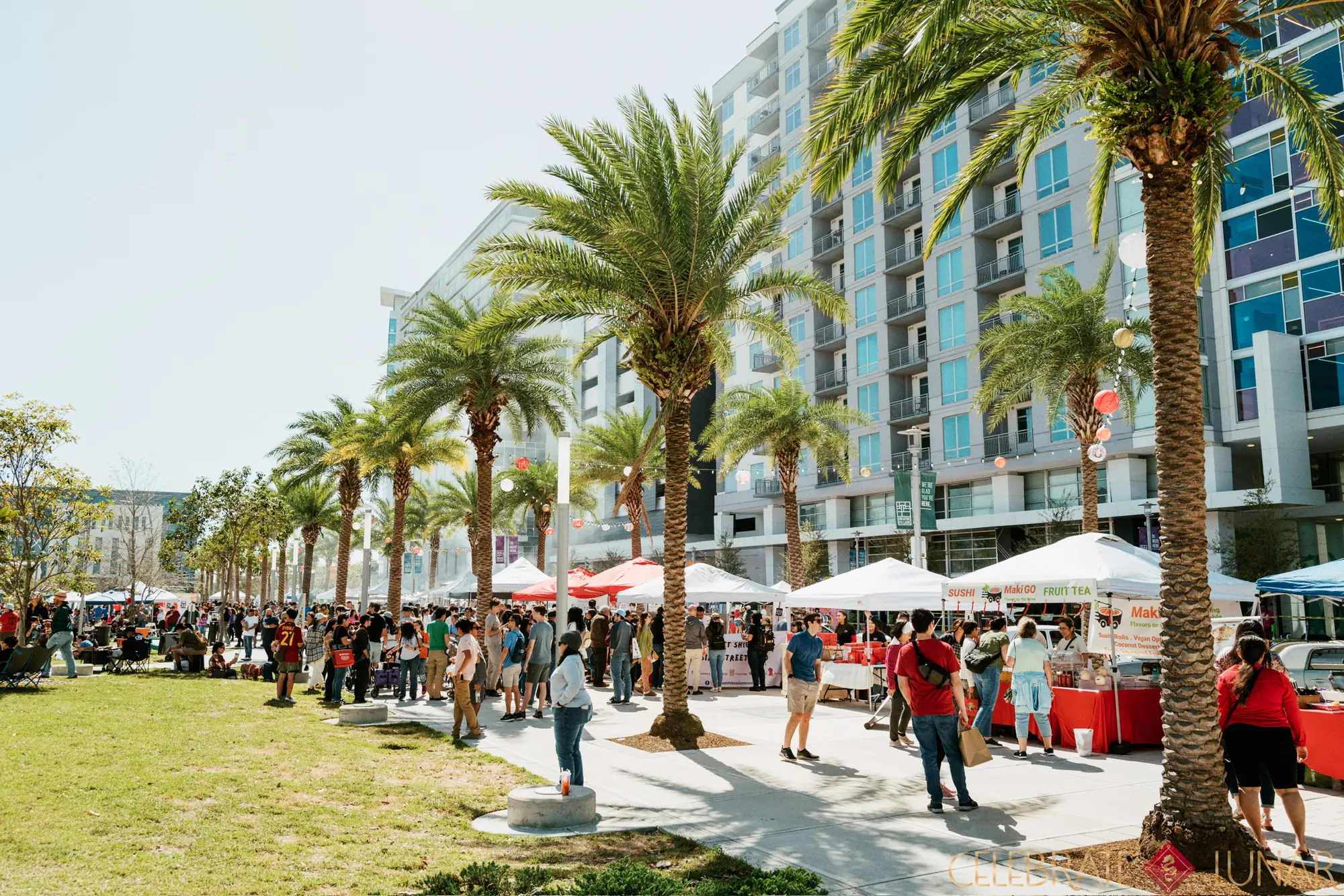 Crowds walking the palm-lined vendor row